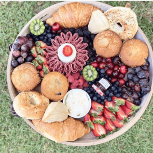 Brunch Board with assorted goodies such as muffins, bagels, fruit, and meats