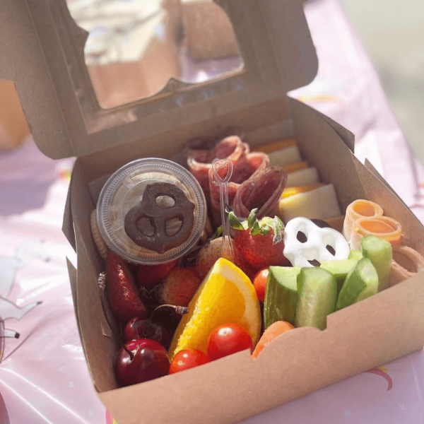 Small Box that contains assortment of meats, cheeses, fruits, and vegetables.